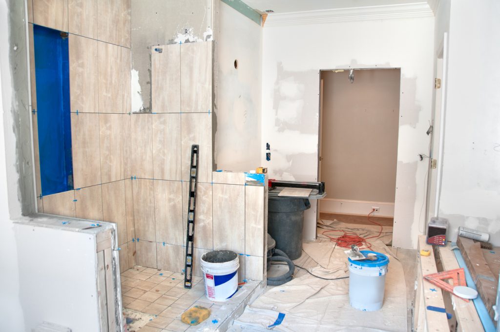 Master Bathroom Remodeling: Tiling in the Shower. The blue paint is a layer of anti-fracture / moisture membrane painted before the tiles are laid. The ground is protected by a piece of drop cloth.