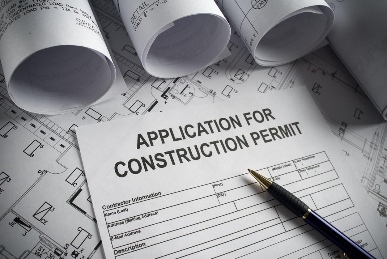 Construction permit application on a background of architectural drawings.